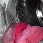 Dreckige Wäsche, die aus einer Waschmaschine hängt.
