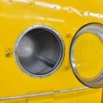 Geöffnete gelbe Waschmaschine in einem Waschsalon