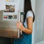 Junge Frau an offener Kühlschranktür