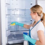 Junge Frau reinigt den Kühlschrank