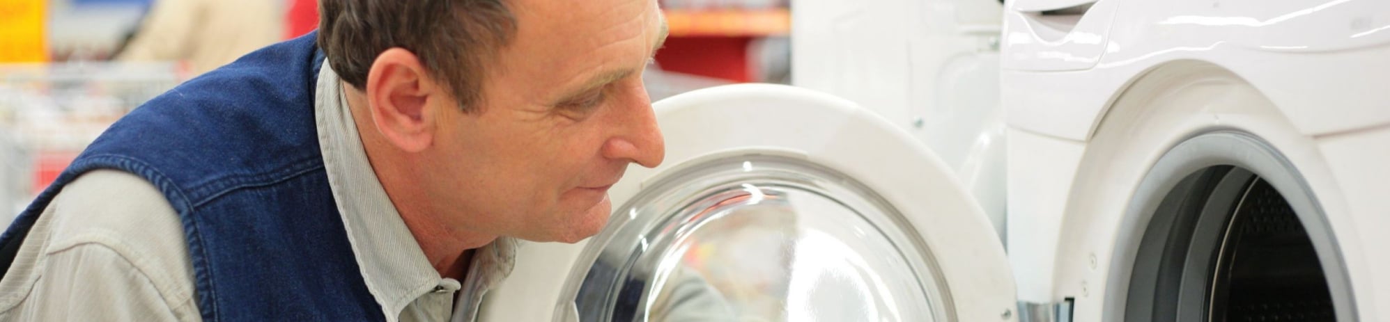 Ein Mann schaut in eine gebrauchte Waschmaschine