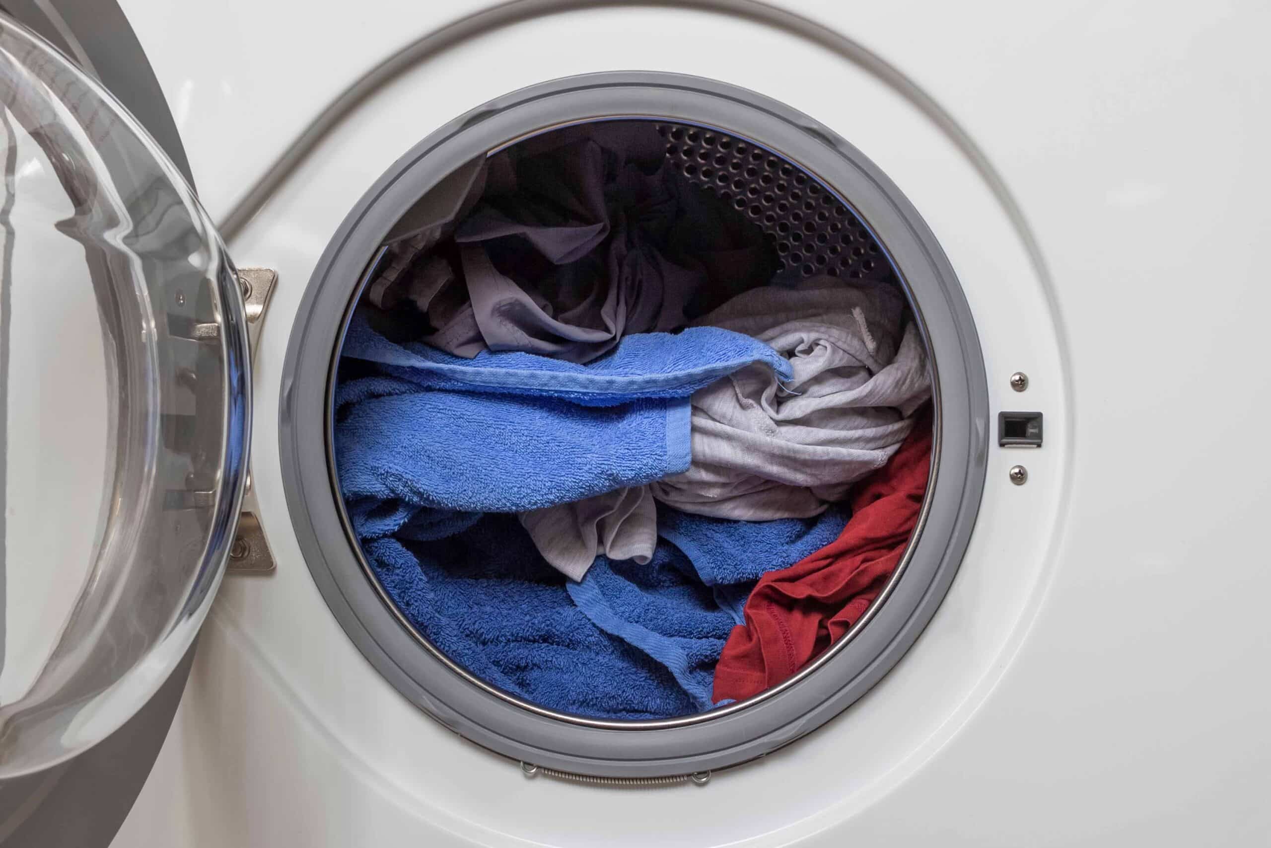 Open door in washing machine with laundry inside.